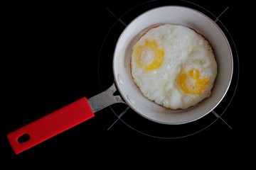 Fried eggs in pan with handle on table, top view