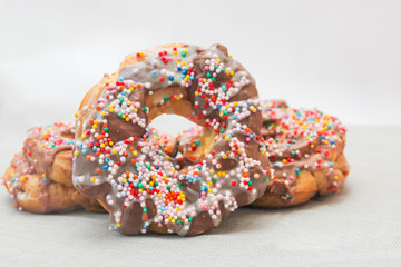 donuts covered with chocolate and sweet confetti close-up on a light background. Chocolate donuts.