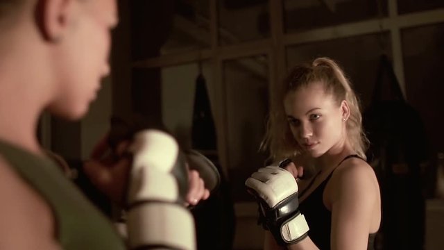 Two kickboxer girls look into each other's eyes before the fight. Duel of views. The camera flies around a slow-motion shot.