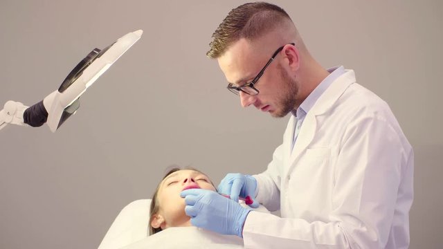 Lip injection plastic surgery. Young male doctor doing lip augmentation