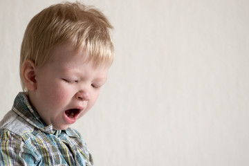 Fototapeta premium Caucasian blond boy misses and yawns. Space for copying