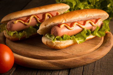 Photo of barbecue grilled hot dog with yellow mustard and ketchup on wooden background. Hot dog...