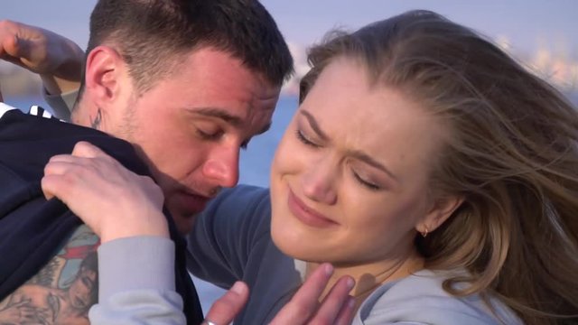 The girl cries at a quarrel with her boyfriend and wants to go away, but he does not let her do it