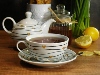 une tasse de thé chaud et fumant avec du miel et du citron, une théière
