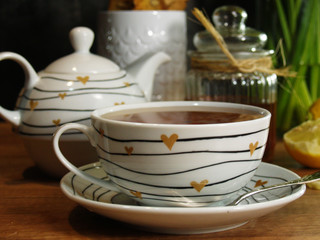 une tasse de thé chaud et fumant avec du miel et du citron, une théière