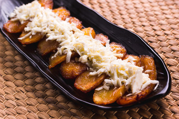 Fried plantain with cheese striped on top, South American food © nehopelon