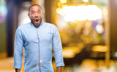 African american man with beard happy and surprised cheering expressing wow gesture at night