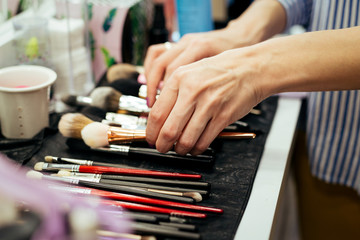 Obraz na płótnie Canvas Female makeup artist with cosmetics at work close-up