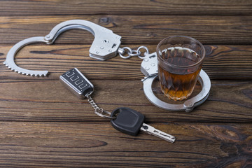 Concept of alcohol driving. Car keys, a glass of whiskey and handcuffs, The idea of arrest is a...