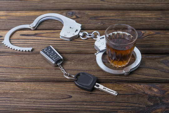 Concept of alcohol driving. Car keys, a glass of whiskey and handcuffs, The idea of arrest is a drunken pusher behind the wheel.
