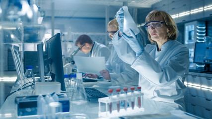 Female and Male Scientists Working on their Computers In Big Modern Laboratory. Various Shelves...