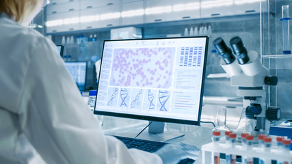 Senior Female Scientist Works with High Tech Equipment in a Modern Laboratory. Her Colleagues are...