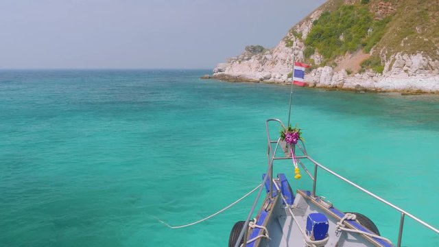 Viewi of cliffy shore of island Rin, Thailand. View from sailing boat with hibiscus on stempost