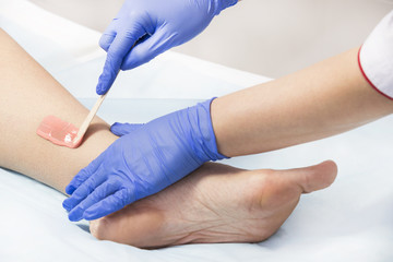 Obraz premium The process of classical wax depilation of female limbs in the beauty salon. 
