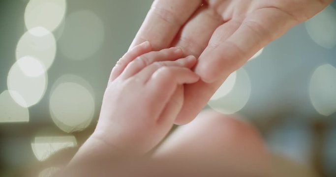 4k.Mother and newborn baby in maternity home. Hand in hand, slow motion, close up. Parenthood. Motherhood.