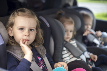 cute small sisters in car seats in the car