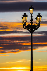 Lighted lanterns against the backdrop of the setting sun on the streets of Madrid