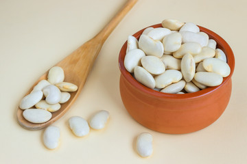 Fototapeta na wymiar Organic large white bean in a ceramic bowl with a large wooden spoon. Concept- healthy food, vegetarianism, observance of religious fasting. Selective focus.