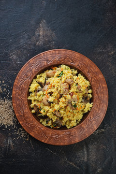 Clay plate with pilaf on a dark brown stone background, vertical shot with copyspace, view from above