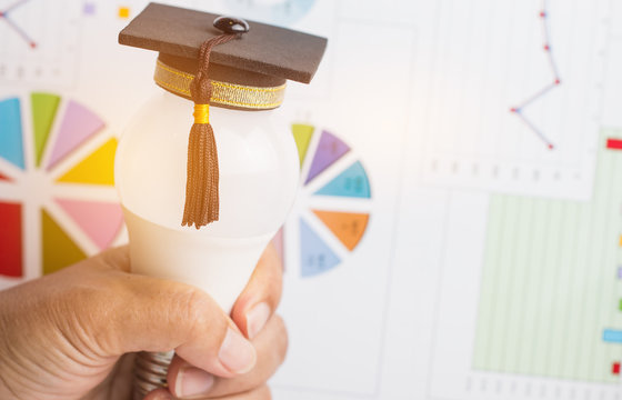 Graduate study, Education knowledge is power concept: Hands holding light bulb with Graduated cap and report background. Conceptual for Educational is Navigation for successs study or business world
