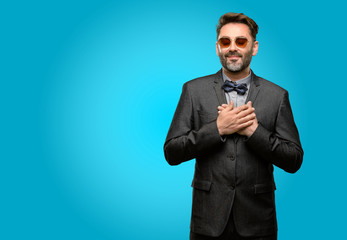 Middle age man, with beard and bow tie with hands in heart, expressing love and health concept