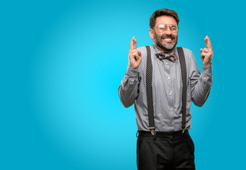 Middle age man, with beard and bow tie with crossed fingers asking for good luck