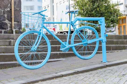 A blue painted bike is used as open boom gate on a road in the downtown of Reykjavik