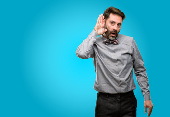 Middle age man, with beard and bow tie holding hand near ear trying to listen to interesting news expressing communication concept and gossip