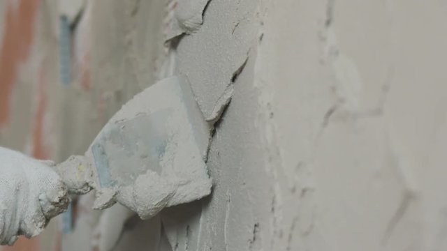 Slow motion handheld shot of worker applying plaster on the wall