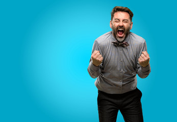 Middle age man, with beard and bow tie happy and excited celebrating victory expressing big success, power, energy and positive emotions. Celebrates new job joyful