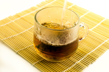 Cup of black tea on a white background and the water flows into the Cup