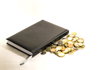 money coins near black notebook on white background
