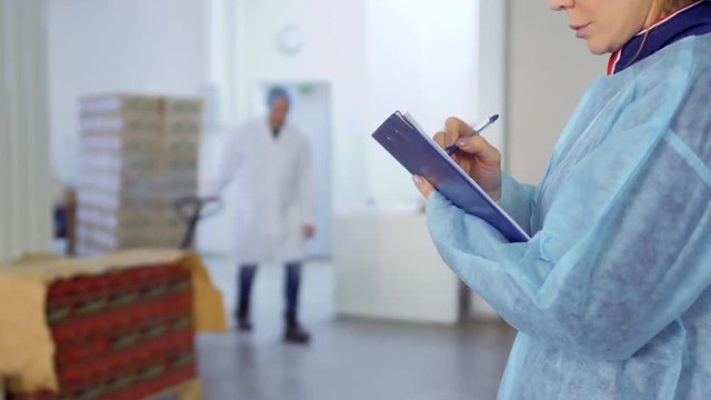 Woman makes notes in her report about work of factory