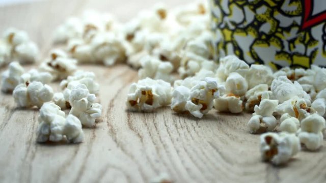 Popcorn in box on black background, close up, rotation wooden table. 4K