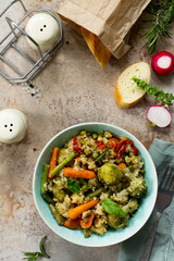 Healthy dietary vegan dish: couscous and vegetables (string beans, brussels sprouts, carrots, sweet peppers, tomatoes) on a stone or slate background. Top view flat lay background.