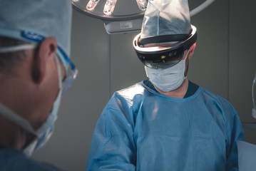 Surgeon using augmented reality holographic hololens glasses while operating in modern operation...