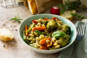 Healthy proper nutrition. Dietary vegan dish: couscous and vegetables (string beans, brussels sprouts, carrots, sweet peppers, tomatoes) on a stone or slate background.