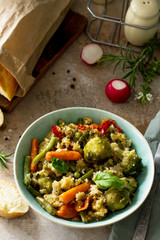 Healthy dietary vegan dish: couscous and vegetables (string beans, brussels sprouts, carrots, sweet peppers, tomatoes) on a stone or slate background.