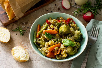 Healthy dietary vegan dish: couscous and vegetables (string beans, brussels sprouts, carrots, sweet peppers, tomatoes) on a stone or slate background.