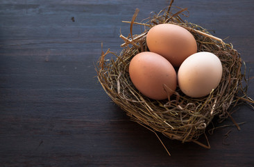 Eggs in a nest on a brown wooden background. Wide format, top view, copy space