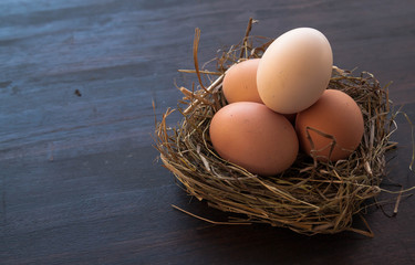 Eggs in a nest on a brown wooden background. Wide format, top view, copy space