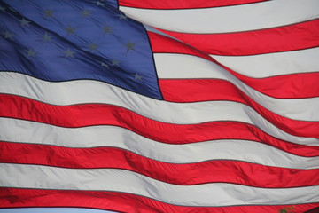 American Flag Stars and Stripes Waving Backlit by the Afternoon Sun Against a Clear Blue Sky