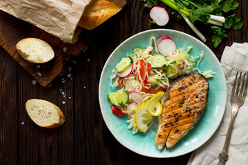 Grilled salmon steak and vegetarian vegetable salad of radish, cucumbers, lettuce salad. Healthy proper nutrition. Top view.