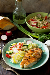 Grilled salmon steak and vegetarian vegetable salad of radish, cucumbers, lettuce salad. Healthy proper nutrition.