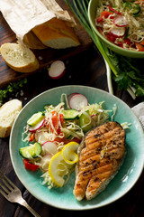 Grilled salmon steak and vegetarian vegetable salad of radish, cucumbers, lettuce salad. Healthy proper nutrition.