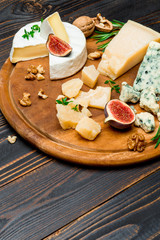 various types of cheese - brie, camembert, roquefort and cheddar on wooden board
