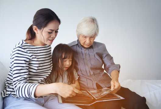 Multi-generation Female Members Of A Family Looking At A Photo Album Together With Their Grandmother, Family Time