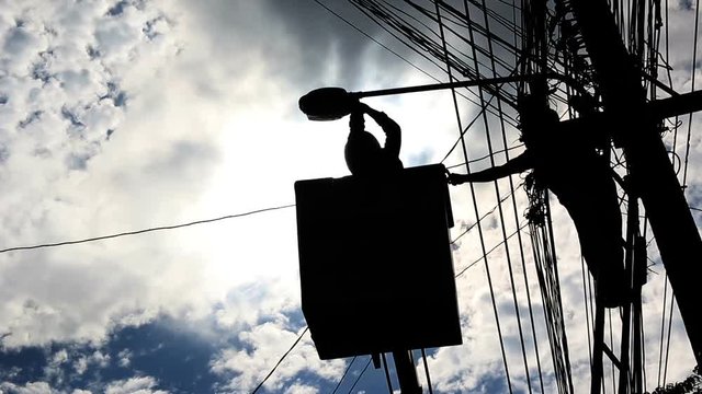 Silhouette of an electrician to repair street lighting
