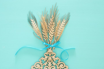 top view of wooden wheat crop decoration over mint background. Symbols of jewish holiday - Shavuot.