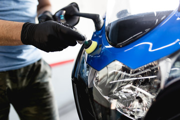 Fototapeta na wymiar Motorcycle detailing - Man with orbital polisher in repair shop polishing motorcycle. Selective focus.
